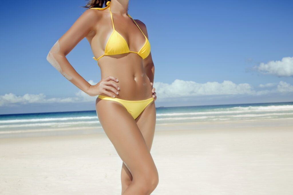 brown hair female body at the beach in a yellow bikini