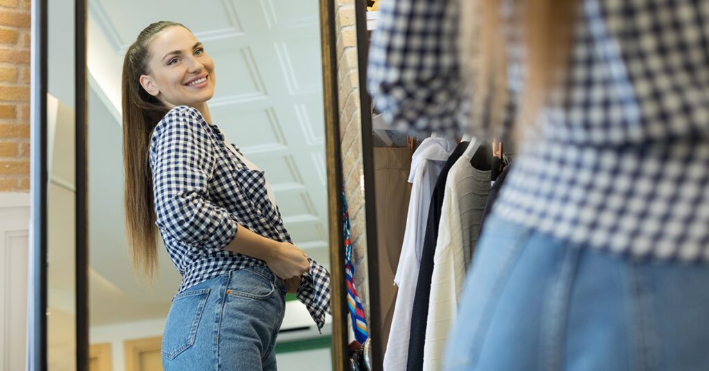 young brown hair female wearing plaid shirt looking in mirror