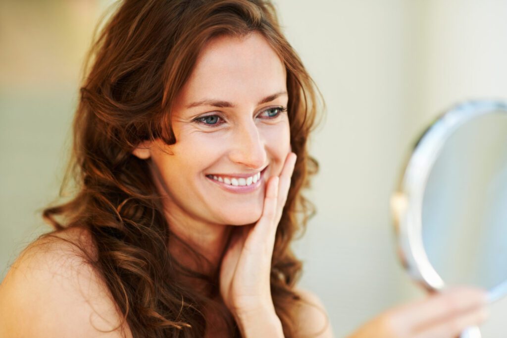 Red hair female looking into mirror and smiling