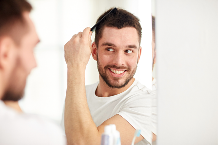 brown hair male combing hair in the mirror