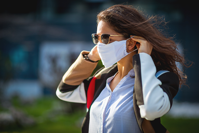 brown hair female walking outside in sunglasses wearing a mask