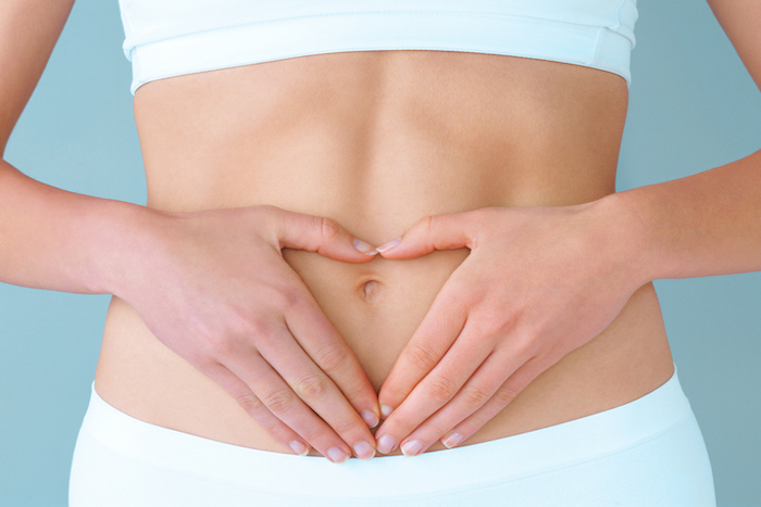 female in white sports bra and pants touching stomach