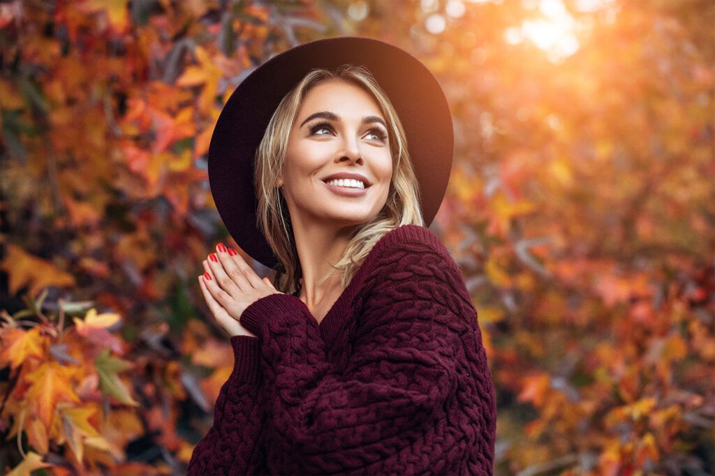 blonde hair female with black hat wearing a red sweater outside in the fall