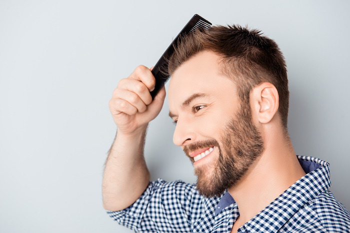 Brown hair male in plaid shirt combing hair