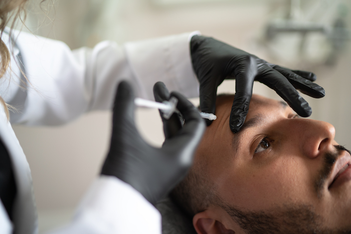 Doctor giving injections to brown hair male patient